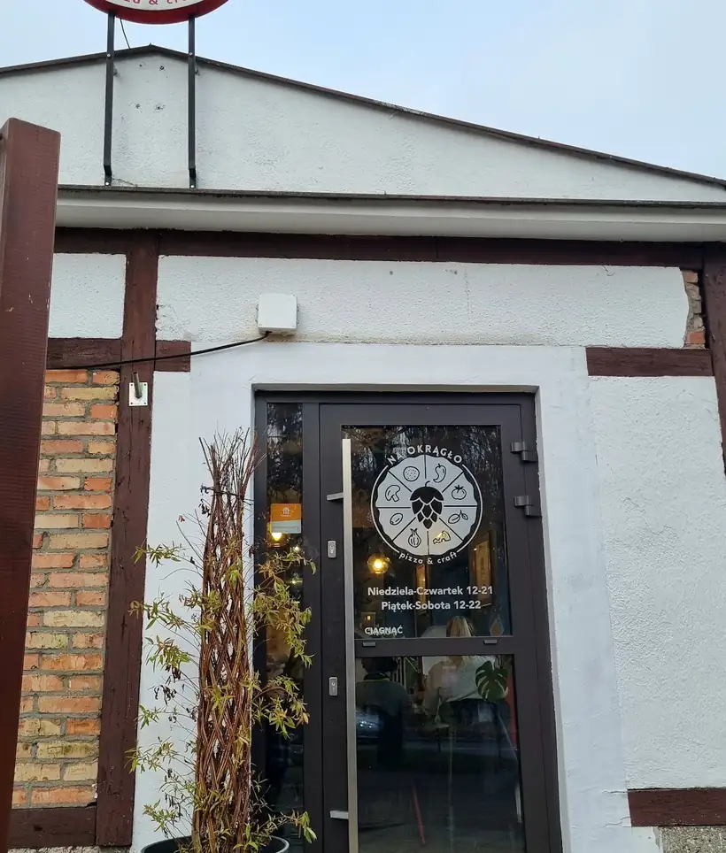 Biały budynek z czerwonym okrągłym szyldem nad drzwiami