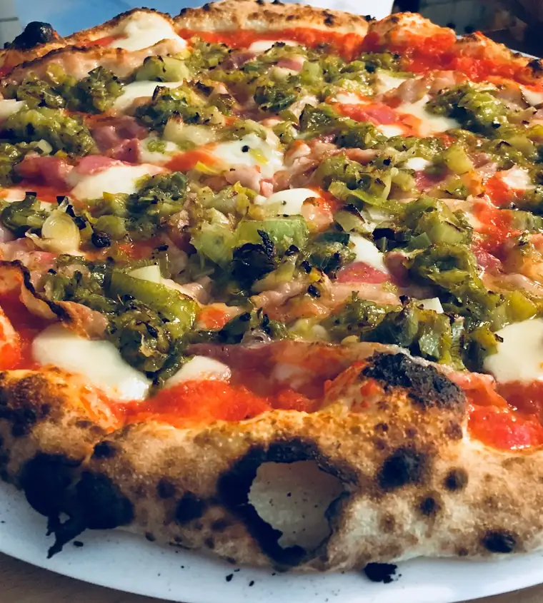 Pizza z przypieczonym brzegiem, zielonymi warzywami i mozzarellą