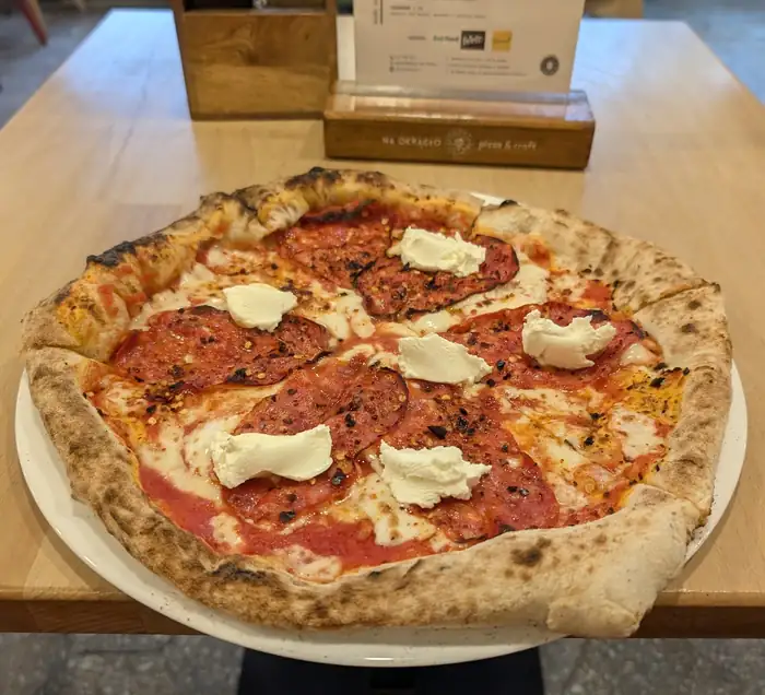 Pizza z salami i kleksami białego sera na talerzu